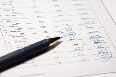 survey with poor, fair, good, excellence answers and a pen. Survey form with a ticks placed in...