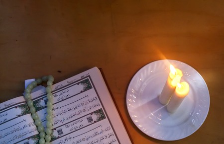 The Holy Quran and lights. Muslims holy book Koran. Open pages of the Holy Quran with praying beads on wooden background. Copy spaceの写真素材