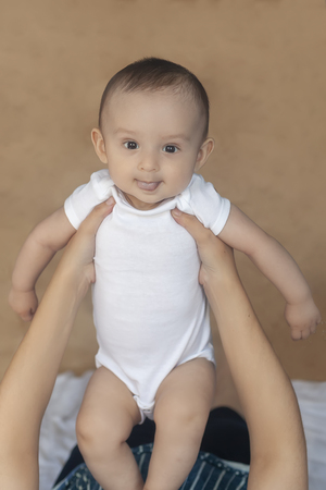 Mother and baby. Mom holding her 6 months baby boy. Beautiful baby boy of six months in his mother's hands. Young middle eastern mother holding in her arms her little son. People, family concept.の写真素材