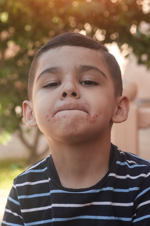 Little boy contorts his face at outdoors. 6 years old kid in summer holidays. Cute little boy fooling around. People, childhood lifestyle concept. Portrait of young child making funny faces.の写真素材