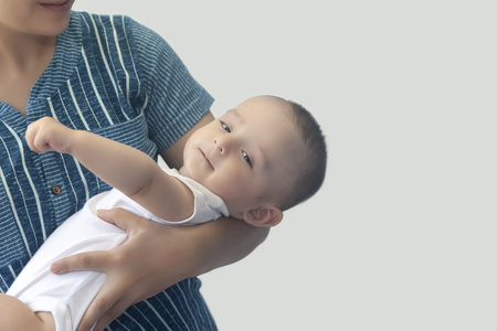 Mother and baby. Mom holding her 6 months baby boy. Beautiful baby boy of six months in his mother's hands. Young middle eastern mother holding in her arms her little son. People, family concept.の写真素材
