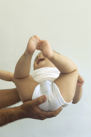 Dad holding 6-month-old baby boy against the white background. Father picking up his baby. Free space. Family conceptの写真素材