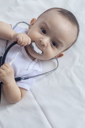 Little cute baby doctor. 6-month old baby boy playing with stethoscope. Kid having fun like a doctor. Medicine and health conceptの写真素材