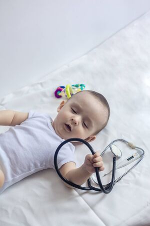 Little cute baby doctor. 6-month old baby boy playing with stethoscope. Kid having fun like a doctor. Medicine and health conceptの写真素材