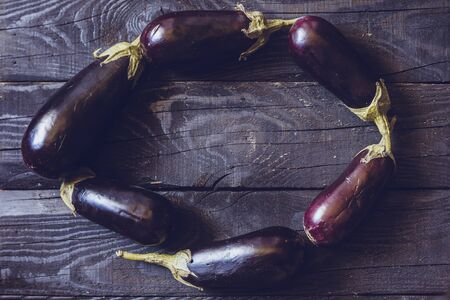 Freshly picked raw eggplants on dark rustic wooden backgroundの写真素材