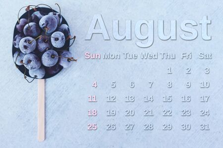 August calendar. Stack of frozen sweet cherries with August month calendar. Summer food background.の写真素材