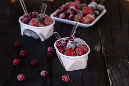 Homemade fresh yogurt. Healthy sweet dessert on dark rustic wooden background. Frozen fruits. Copy spaceの写真素材