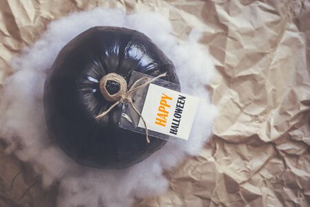 A big black pumpkin with an empty white tag. Autumn pumpkin with label - Happy halloween. Fall, Halloween and Thanksgiving concept. Copy spaceの写真素材