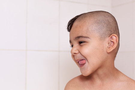 Portrait of a little middle eastern boy at the bathroom. 6-year-old pretty kid with half-cut hair at...