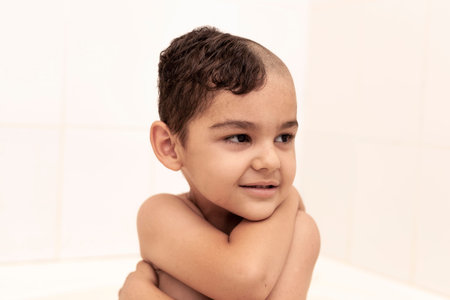 Portrait of a little middle eastern boy at the bathroom. 6-year-old pretty kid with half-cut hair at...