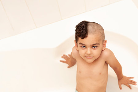 Portrait of a little middle eastern boy at the bathroom. 6-year-old pretty kid with half-cut hair at...