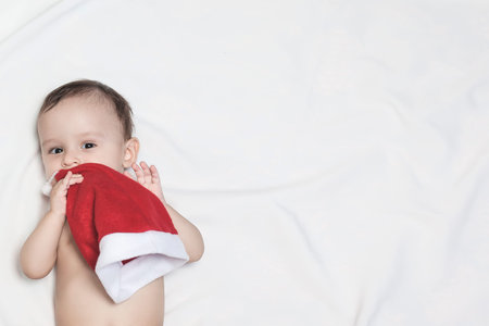 9-month baby boy with Santa Claus hat. Christmas morning. Little kid playing. Adorable baby boy with...