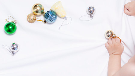 Baby boy playing with Christmas tree balls and toys, Copy space. Cute and adorable baby playing at...