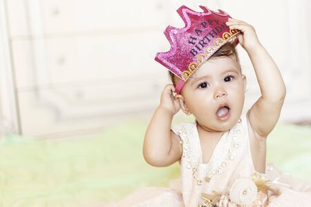 First birthday. Little cheerful baby girl with crown celebrating her first birthday party. A funny baby girl dressed as a princessの写真素材