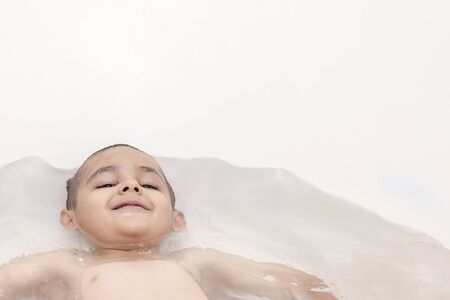 Boy takes a bath. 5-6 years kid having water fun in bathroom. Copy spaceの写真素材