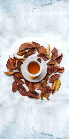 Autumn conceptual background. A cup of hot tea with fall leaves and empty spaceの写真素材