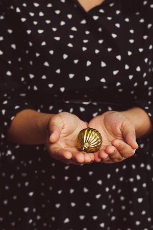Christmas toy in woman hands. Young woman holding xmas tree toy. Close-up view
