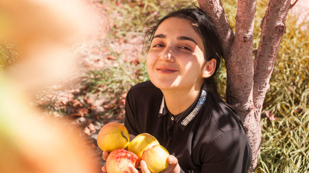 Portrait of beautiful middle-eastern woman at apple garden. Young female posing with freshly picked...