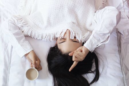 Beauty woman drinking ordering coffee in bed. Female waking up in morning. Young beautiful woman in bed with cup of coffee. Cute lady waking up. Breakfast in cozy bedroom. Waking up with sweet dreamsの写真素材