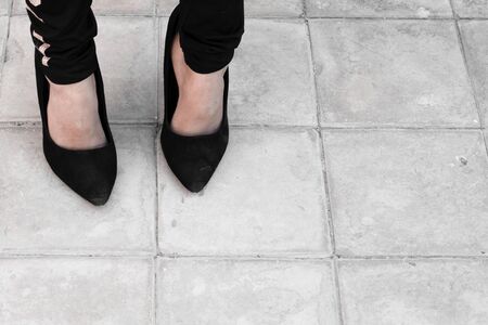 12 years old girl wearing mothers big shoes. A little girl in black oversized high heel shoes. Close-up view of legsの写真素材