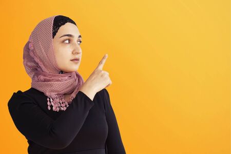 Portrait of stylish Iranian woman. Elegant Muslim woman in hijab pointing with hands to empty space. Copy space for your text. Beautiful Muslim female isolated. Banner, advertising ready stock imageの写真素材