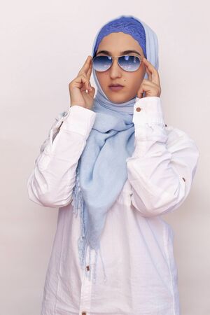 Stylish and elegant Muslim woman in traditional Islamic clothing. Portrait of beautiful Iranian girl in hijab and trendy sunglasses. Stock photo of Islamic clothing, fashion. Isolated on whiteの写真素材