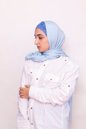 Elegant Muslim woman in white shirt and bright blue hijab. Stylish Iranian girl in Muslim clothing....