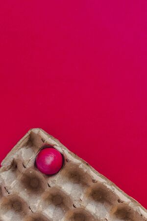 One red Easter egg. Egg carton on the red background. Festive background. Happy Easter. Vertical Imageの写真素材