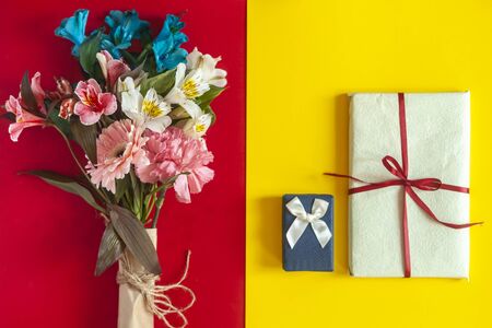 A colorful spring flowers bouquet with a present box on the multicolored paper background. Possible concepts of birthday, valentines day, anniversary, mothers day, wedding, loveの写真素材