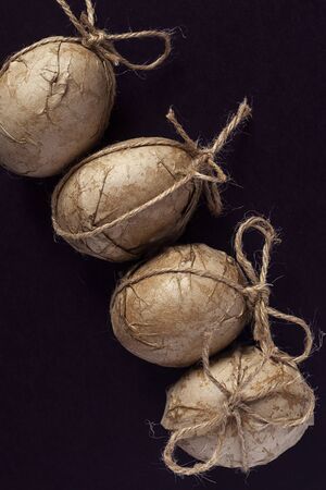Easter eggs decorated with crafty paper and ribbon on the dark backgroundの写真素材