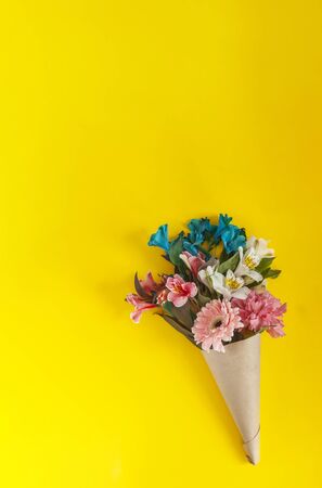 A bouquet of fresh spring flowers on the bright yellow background. Top view of spring floral background with copy spaceの写真素材