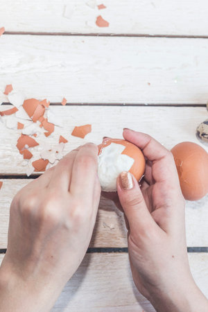 Hands of an unrecognizable woman cleaning boiled eggs. Egg cleaning process. Female preparing...