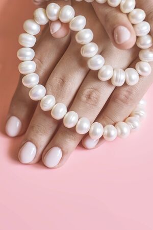 Beautiful female hands with manicure holding pearls. Woman showing hands with stylish trendy female manicure. Hand skin careの写真素材