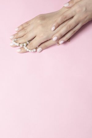 Beautiful female hands with manicure holding pearls. Woman showing hands with stylish trendy female manicure. Hand skin careの写真素材