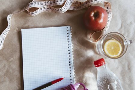Diet planning. Meal plan - healthy food: Fresh water bottle, skipping rope and an apple with an empty notepadの写真素材