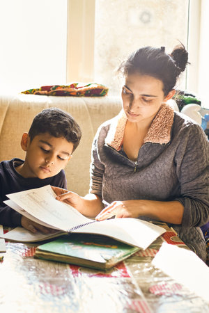Parenting help with homework. Authentic photo of young mother helping her little boy do homework