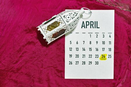 April monthly calendar on the red silk textile background. Islamic Ramadan Eid festive background with Islamic traditional lanternの写真素材