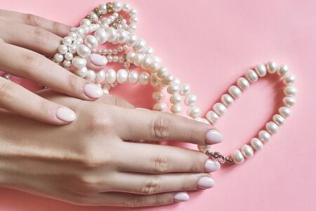 Beautiful female hands with manicure holding pearls. Woman showing hands with stylish trendy female manicure. Hand skin careの写真素材