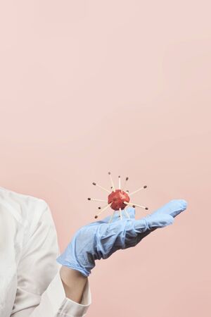 Female doctor in protective medical uniform holding coronavirus. Scientist virologist holding in hands handmade model of new Coronavirus or COVID-19の写真素材