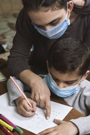Distance education. Mother helps pre-school kid to do lessons. Education at quarantine time. Protection of Children during the Coronavirus Pandemicの写真素材