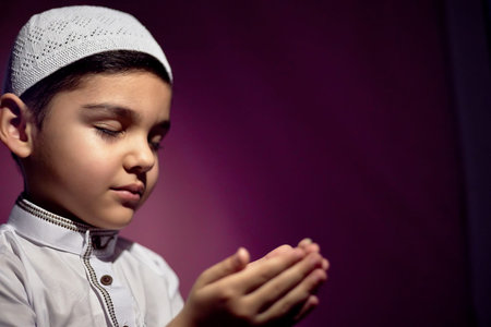 Muslim child praying in the mosque. Little middle-eastern boy prays to God and thanks. Peace and...
