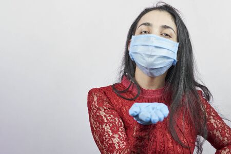 A young middle-eastern woman wearing evening dress and surgical mask. Beauty female in surgical mask celebrating. Portrait of middle-aged lady having fun during quarantine against covid-19 pandemicの写真素材