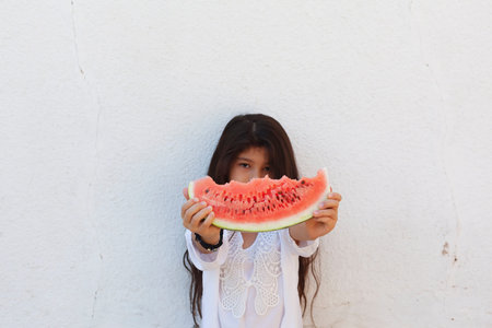 Portrait of a beautiful teen girl eating watermelon at outdoors. A little girl holding in hands big...
