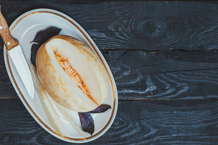 Slices of sweet organic summer melons on the dark wooden background. Sliced ripe melon on wood. View...