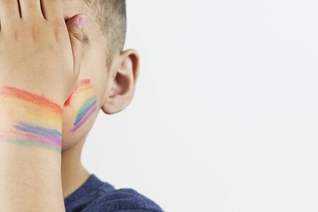 Close-up view of little boy half-face with painted rainbow flag on cheeks. Half face portrait of LGBTQ family child. Pride day, LGBT family, sexual rights and equality conceptsの写真素材