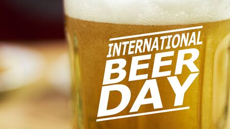 Close-up view of beer glass with text overlay on it - International beer day. Glass of cold light beer with bubble froth in glass. Drink alcohol, celebration, party, holiday conceptsの写真素材