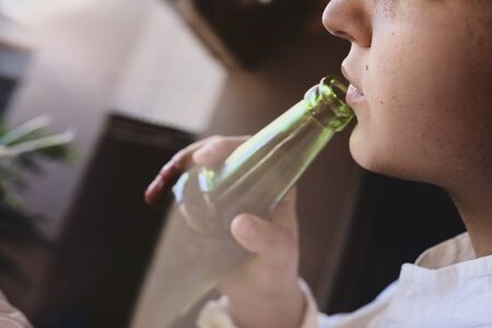 An unrecognizable female drinking beer while driving car. Concepts of driving under the influence, drunk driving or impaired drivingの写真素材