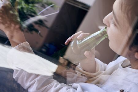 An unrecognizable female drinking beer while driving car. Concepts of driving under the influence, drunk driving or impaired drivingの写真素材