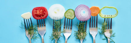 Sliced pieces of fresh vegetables on the forks. Fresh organic onion, garlic, carrot and bell pepper...
