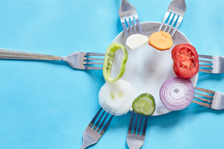 Sliced pieces of fresh vegetables on the forks. Fresh organic onion, garlic, carrot and bell pepper...